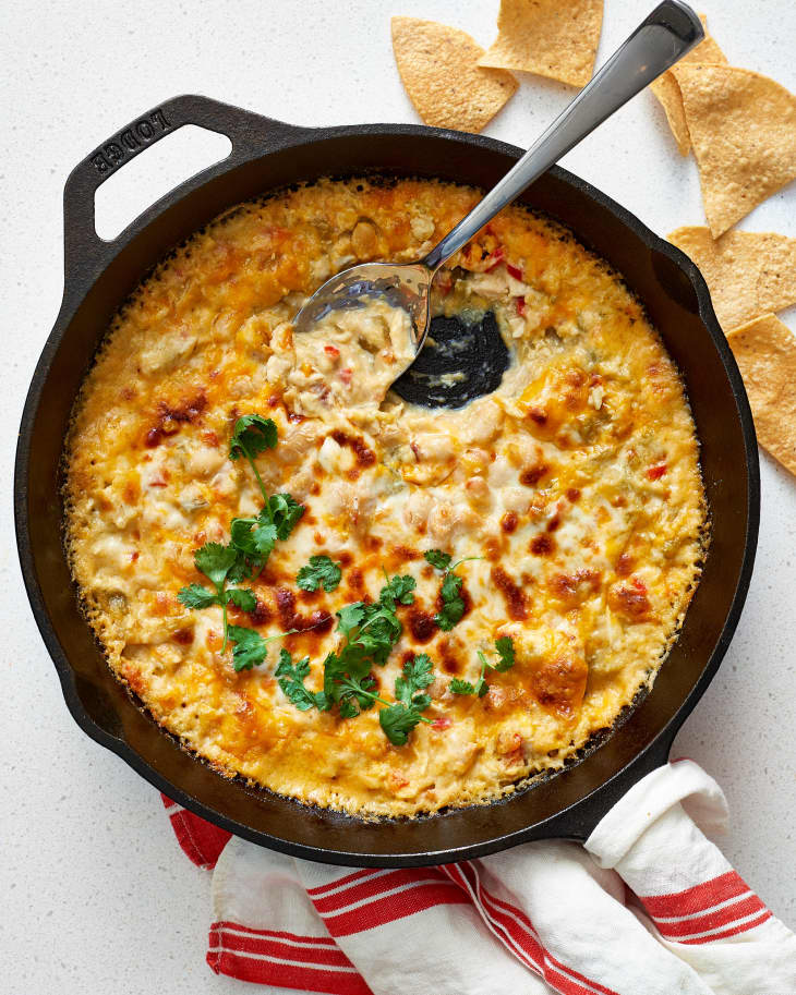 Cheesy baked dip in a cast iron skillet with cilantro garnish, served with tortilla chips.