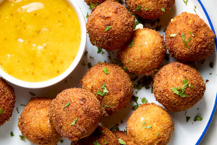 overhead shot of a plate of fried goat cheese balls, with a side of mustard dipping sauce.