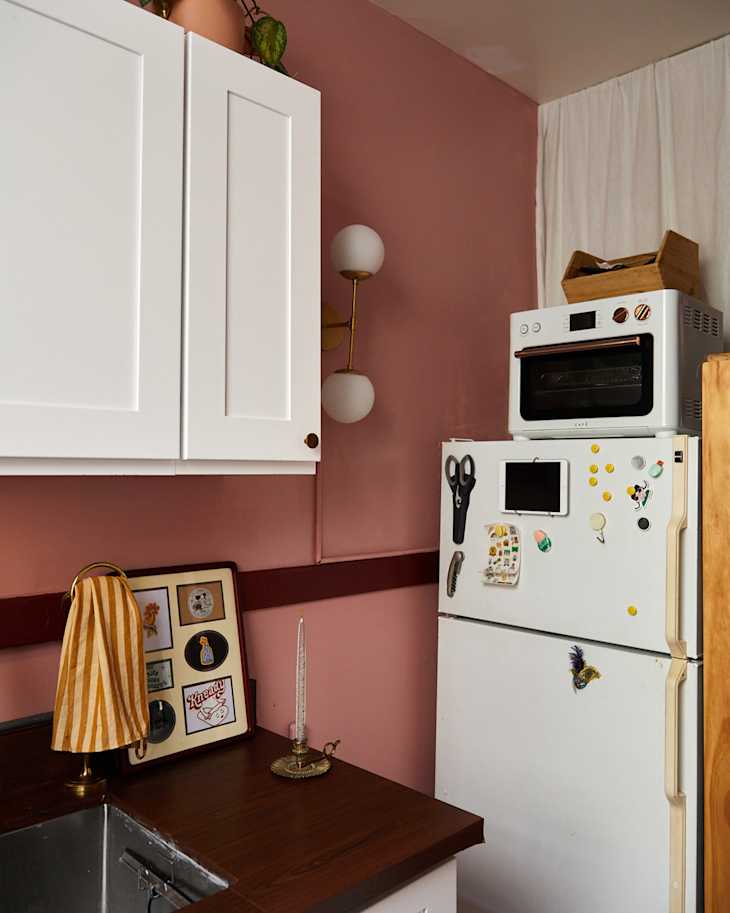Sconce next to cabinets in pink painted kitchen.