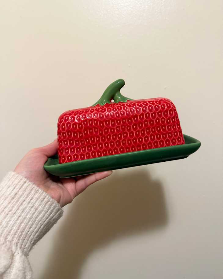 Someone holding strawberry butter dish.