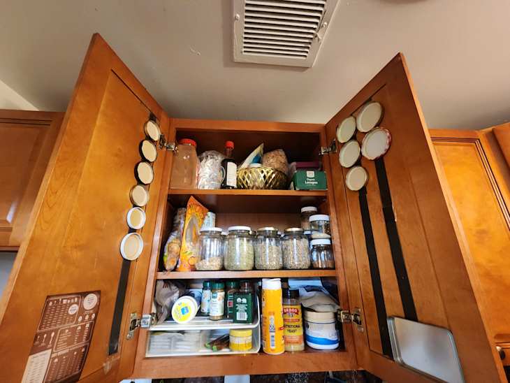 Kitchen cabinet with magnetic strips holding metal lids for jars.