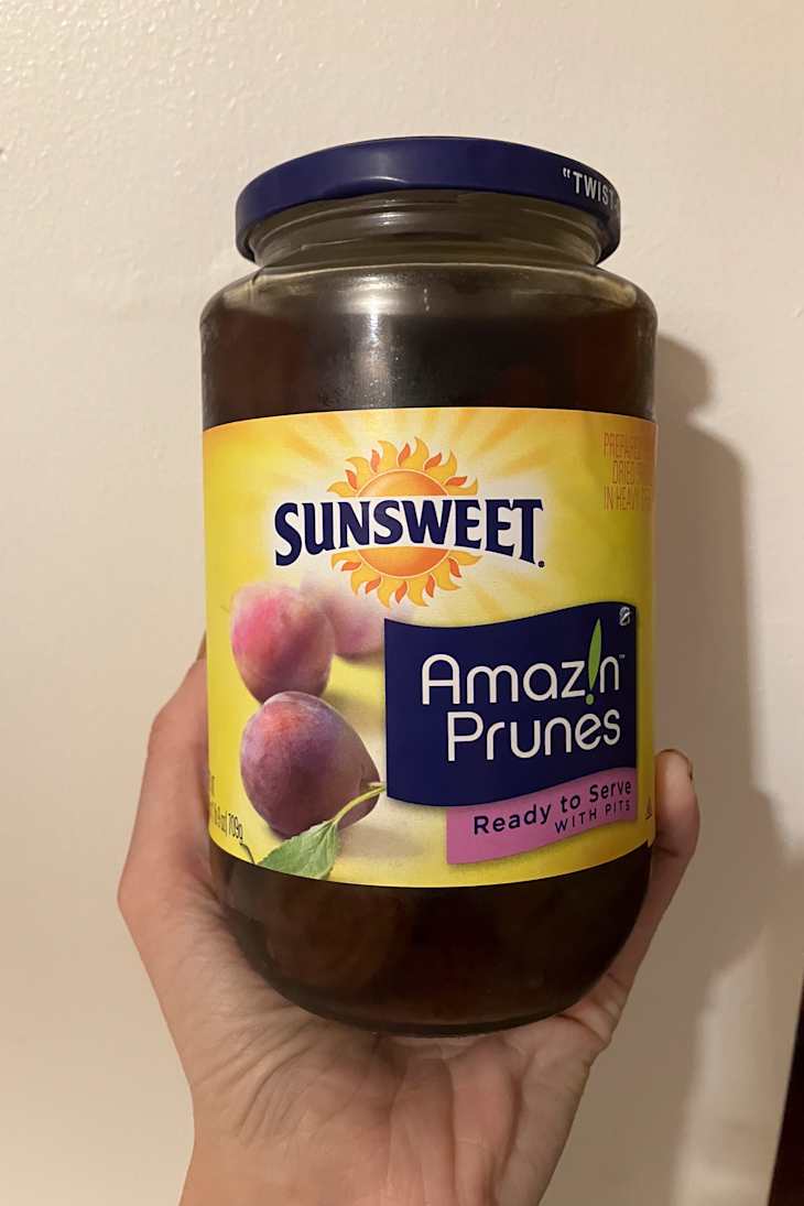 A hand holding a jar of Sunsweet Amazin' Prunes.