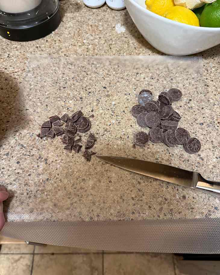 Someone cutting up chocolate on a disposable cutting board