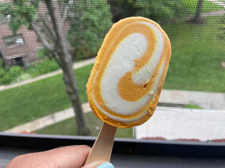 Someone holding passion fruit dreamsicle ice cream.