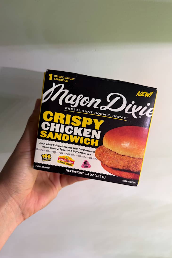 Frozen Mason Dixie Crispy Chicken Sandwich box held in hand, featuring a fluffy potato bun and crispy chicken patty.