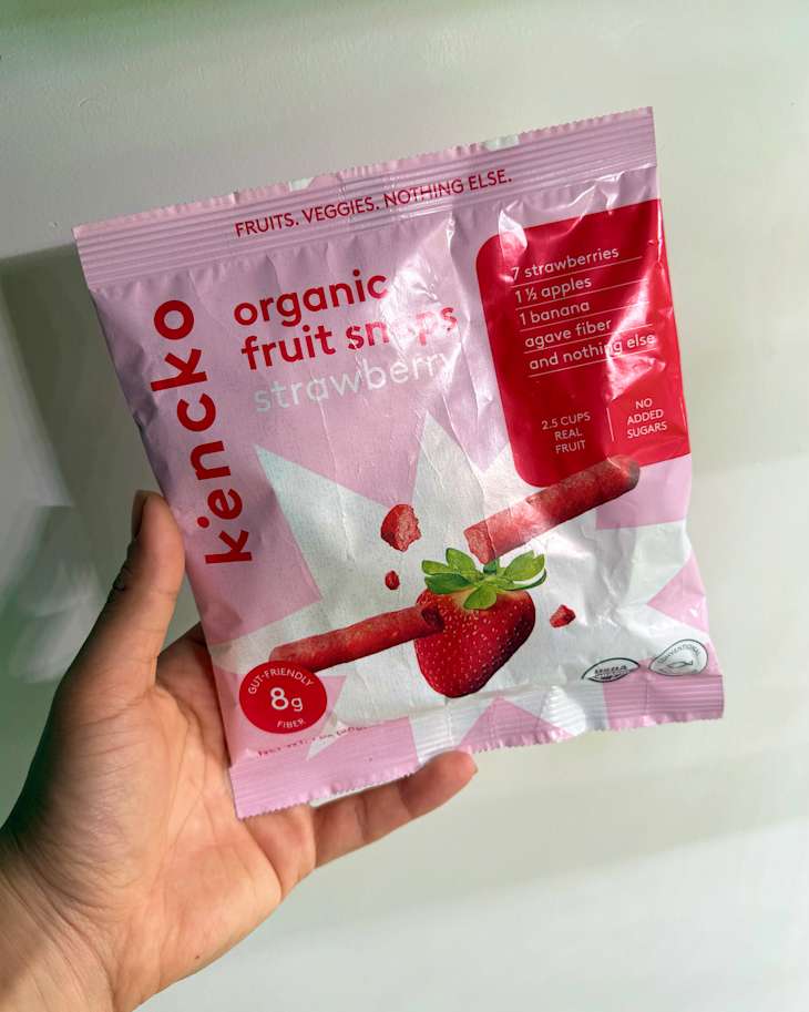 Someone holding a bag of Kencko Organic Fruit Snaps in strawberry flavor