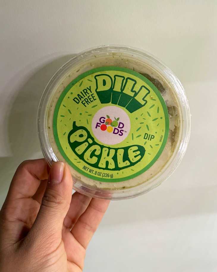 someone holding up a package of Good Foods Dairy Free Dill Pickle Dip