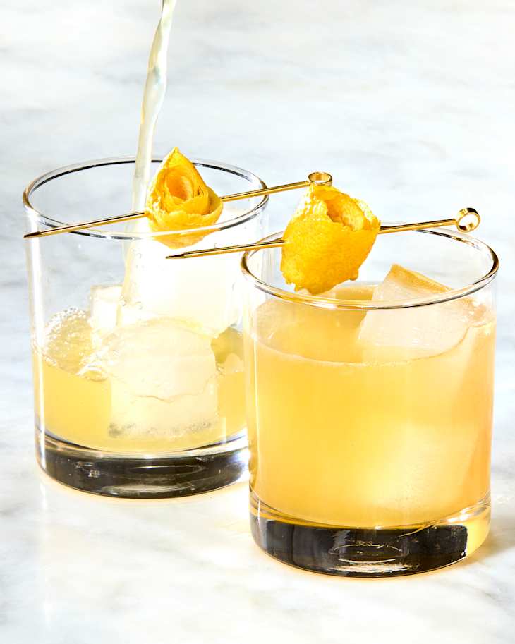 Two penicillin cocktail on a marble background, the back one getting poured in.
