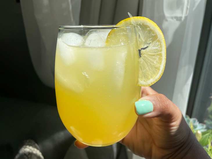 someone holding a cortisol cocktail in glass with lemon slice