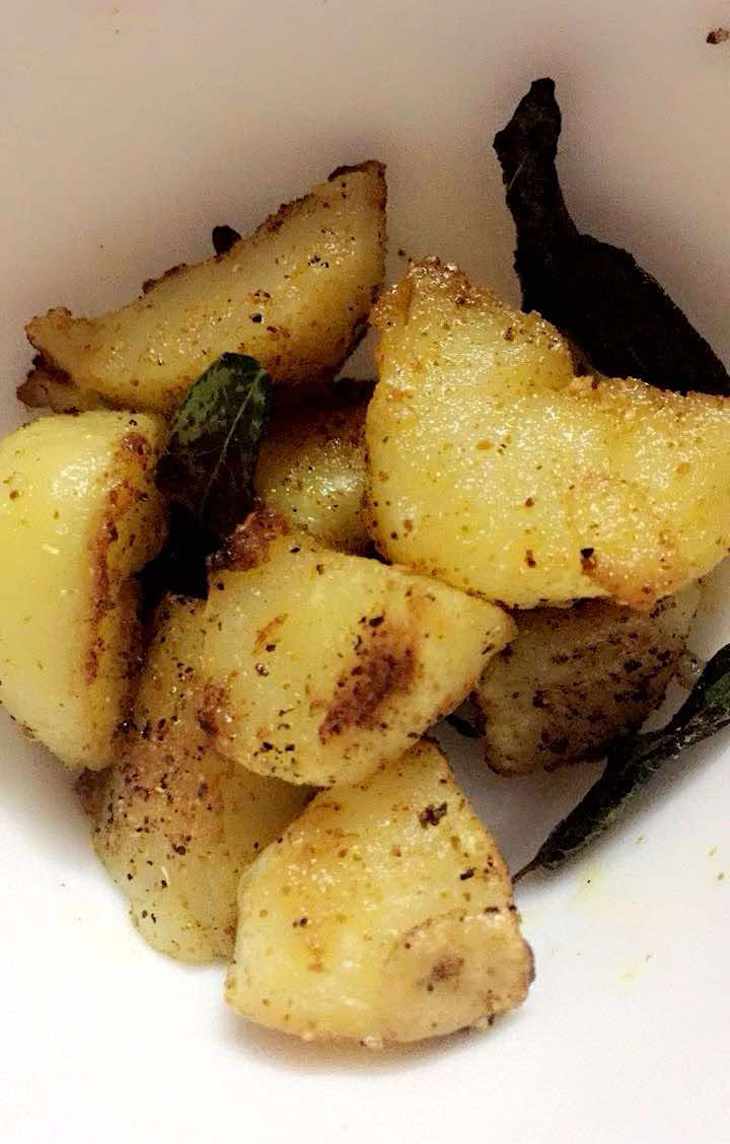 Golden-brown roasted potatoes seasoned with spices and garnished with curry leaves.