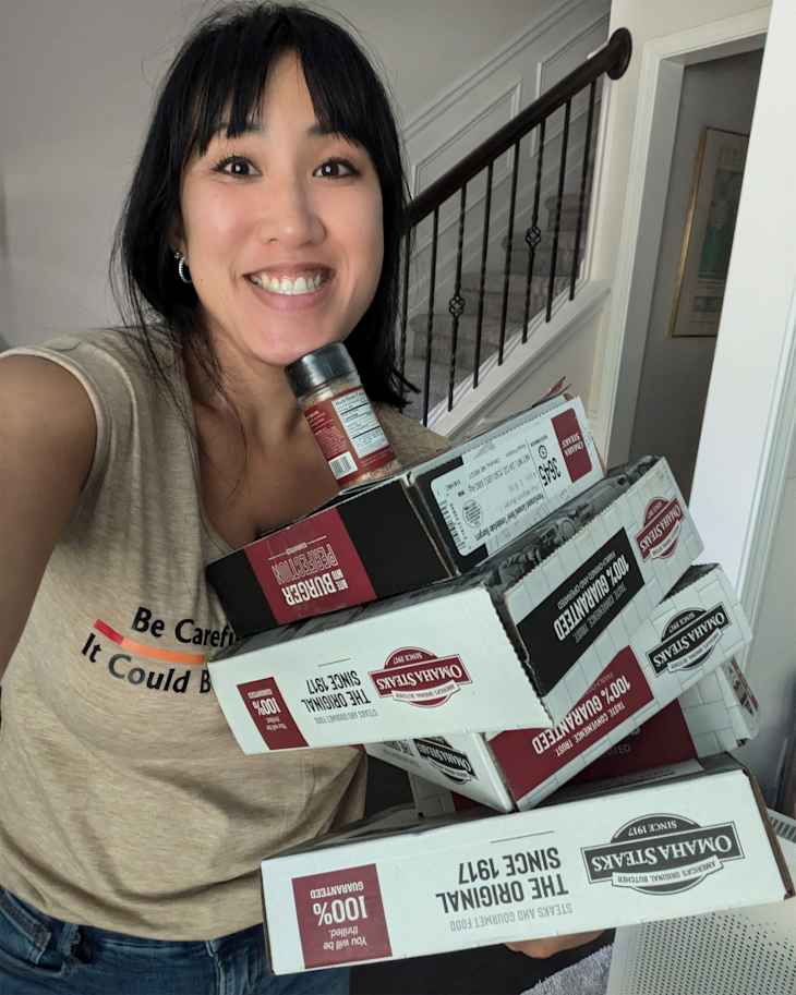 Someone holding boxes of steaks.