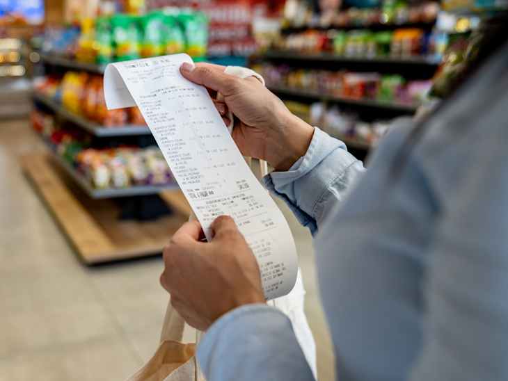 Close-up on a woman shopping at a grocery store and checking her receipt while exiting