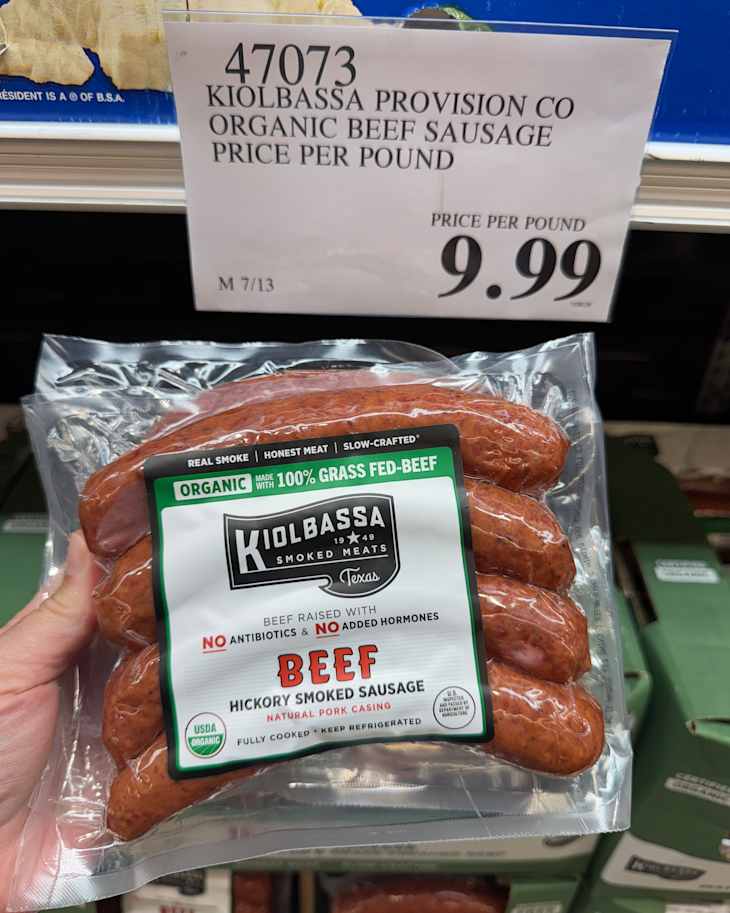 Someone holding package of beef sausage.