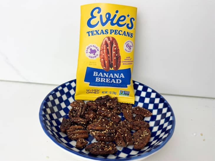A blue and white checkered bowl filled with Evie's Texas pecans, with a yellow packaging labeled "Banana Bread" in the background.