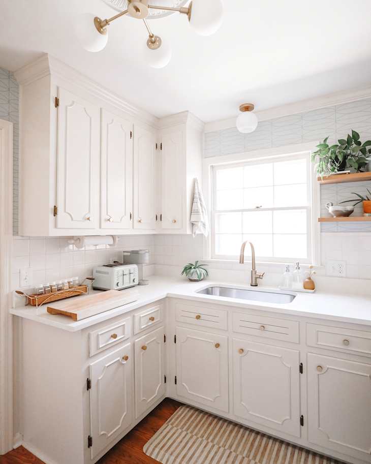 white kitchen with white cabinets with modern pulls, and updated light fixtures after makeover