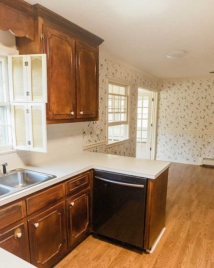 kitchen with dark wood cabinets and outdated wallpaper before makeover