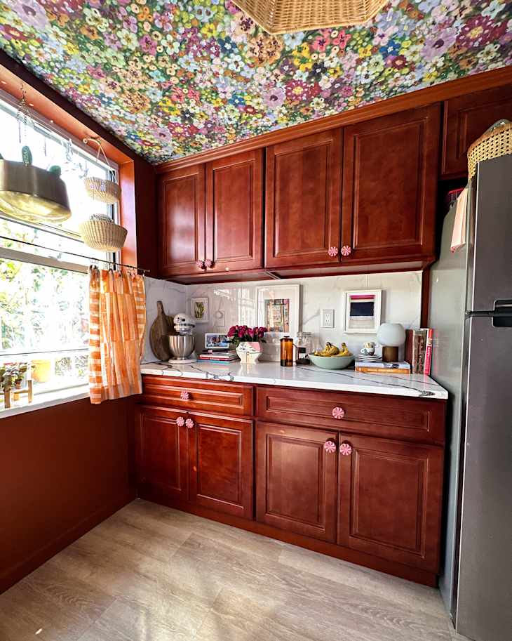 Colorful floral wallpaper mounted on ceiling of redecorated kitchen.