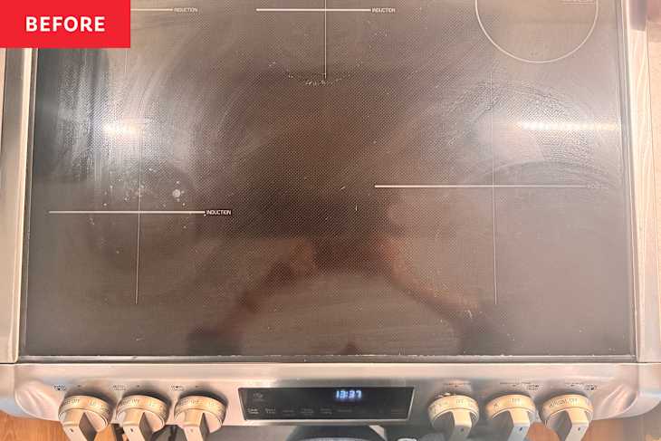 Induction cooktop with visible smudges and stains, featuring control knobs and a digital display.