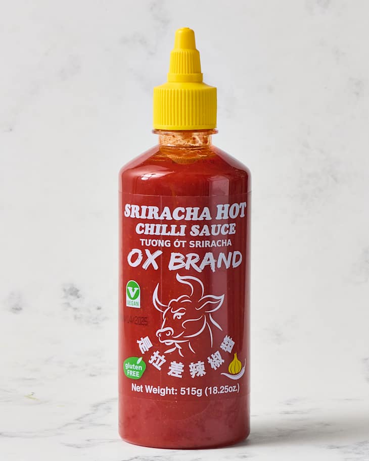 Ox Brand Sriracha hot chili sauce bottle with a yellow cap, featuring a bull logo and vegan, gluten-free labels.