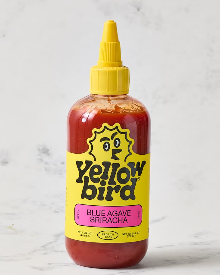 Yellow Bird Blue Agave Sriracha sauce bottle with yellow cap and label featuring a cartoon bird, labeled "Blue Agave Sriracha."