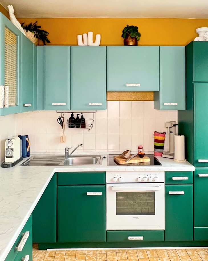 Green painted cabinets in kitchen with yellow walls.