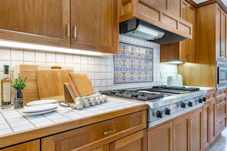 spacious mid century craftsman home kitchen with tiled countertops white appliances dining areas bar stools in white pine coloured cabinets mosaic backsplash