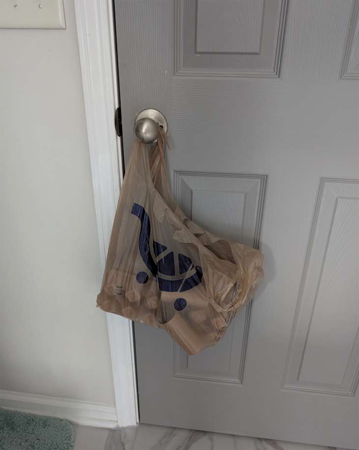 Bag of paper towel rolls behind bathroom door.