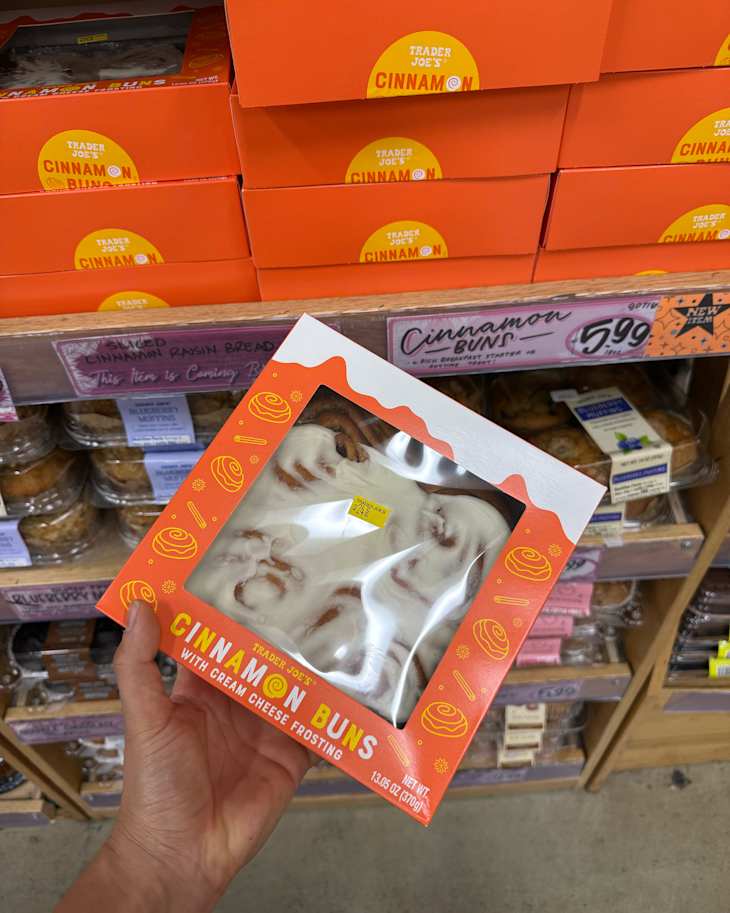 Someone holding box of Trader Joe's cinnamon rolls in store.