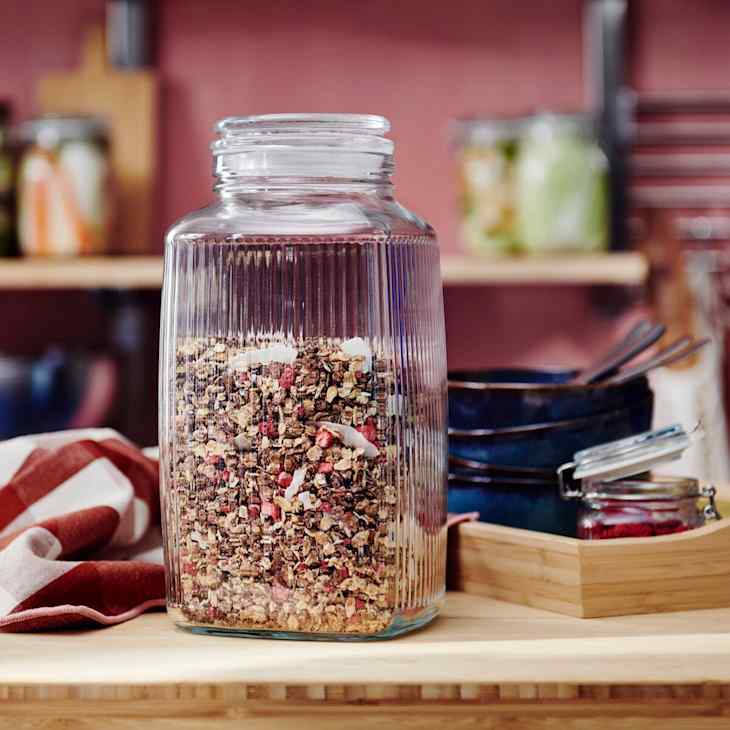 Glass jar filled with colorful granola on a wooden surface.