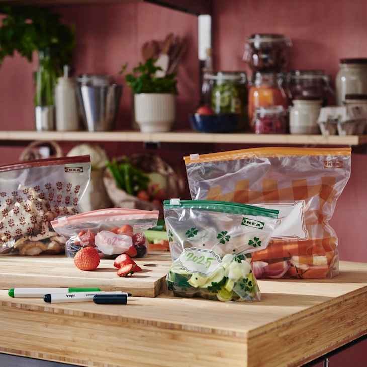 Various food items in labeled storage bags on a wooden countertop.