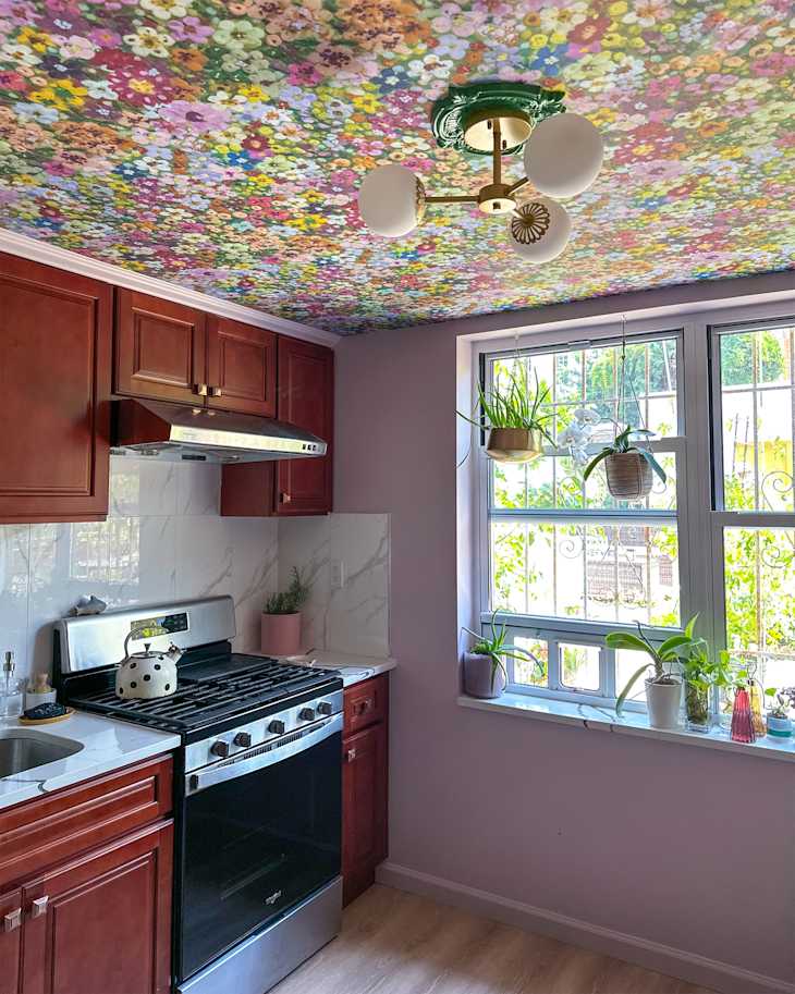Floral wallpaper mounted on ceiling of colorful kitchen.