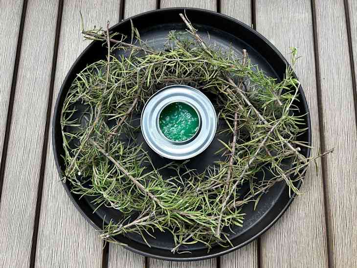 A plate of rosemary sprigs on a deck with a sterno can in the middle