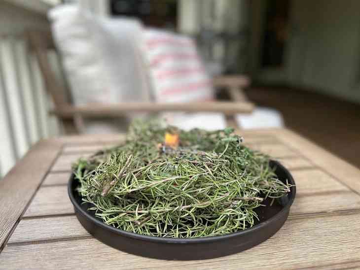 A plate of rosemary sprigs on a deck with a sterno can in the middle