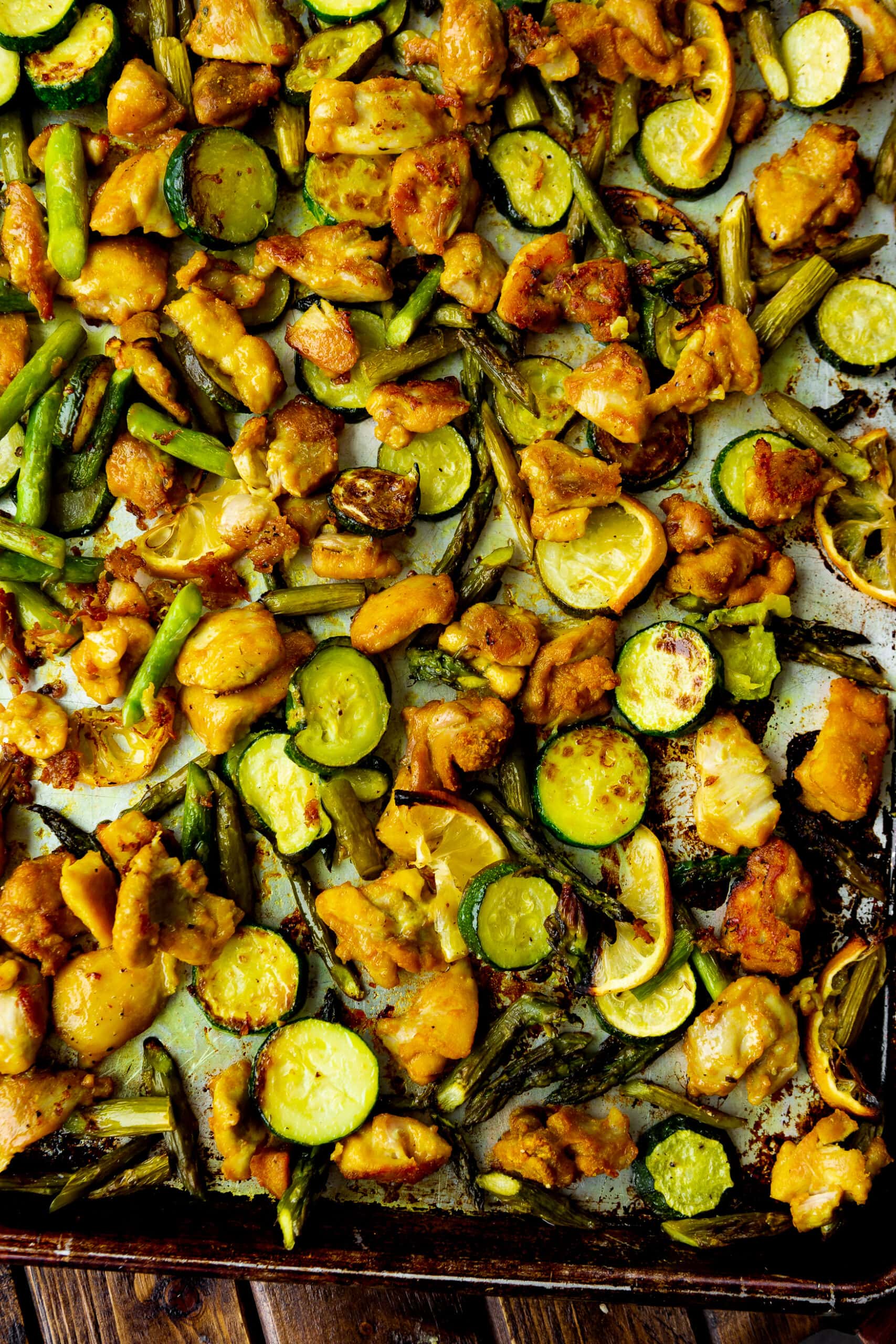 Oven-Roasted Chicken Legs with Zucchini and Corn on a Baking Sheet