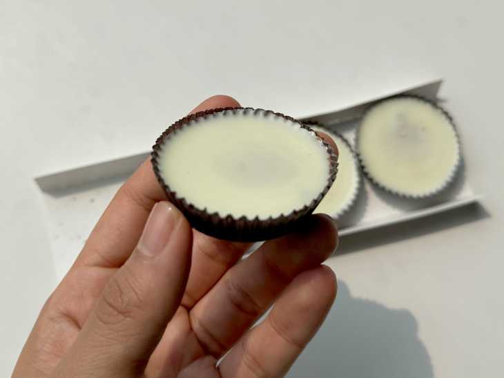 someone holding a Reese's Oreo cup in front of the rest of the cups in the package