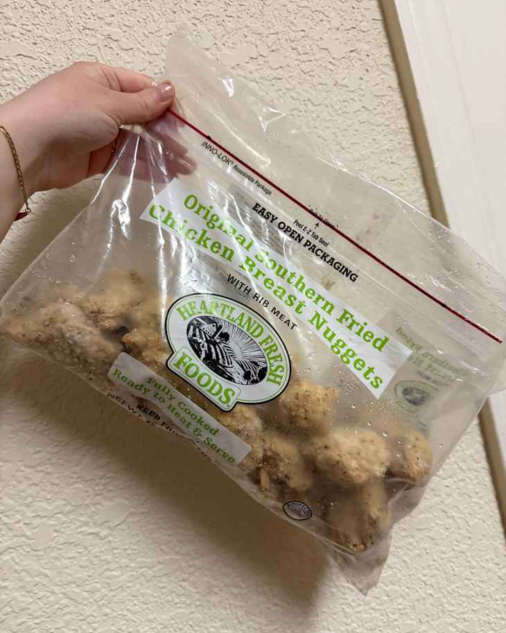 Someone holding package of Heartland Foods Chicken nuggets.