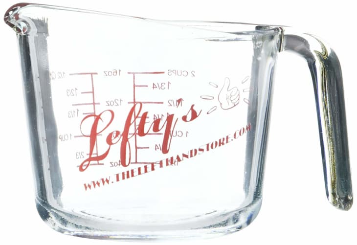Glass measuring cup with red "Lefty's" logo, measurement markings, and a website URL.