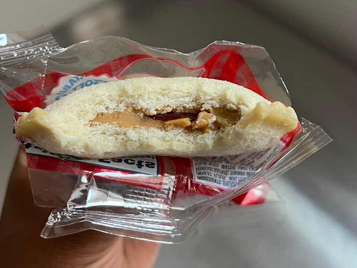 Someone holding a partially eaten Smucker's Strawberry Uncrustable so the inside is visible