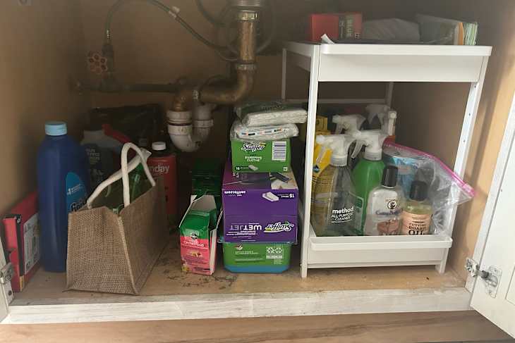 Cleaning products organized under kitchen sink with Yamazaki pull out shelf.
