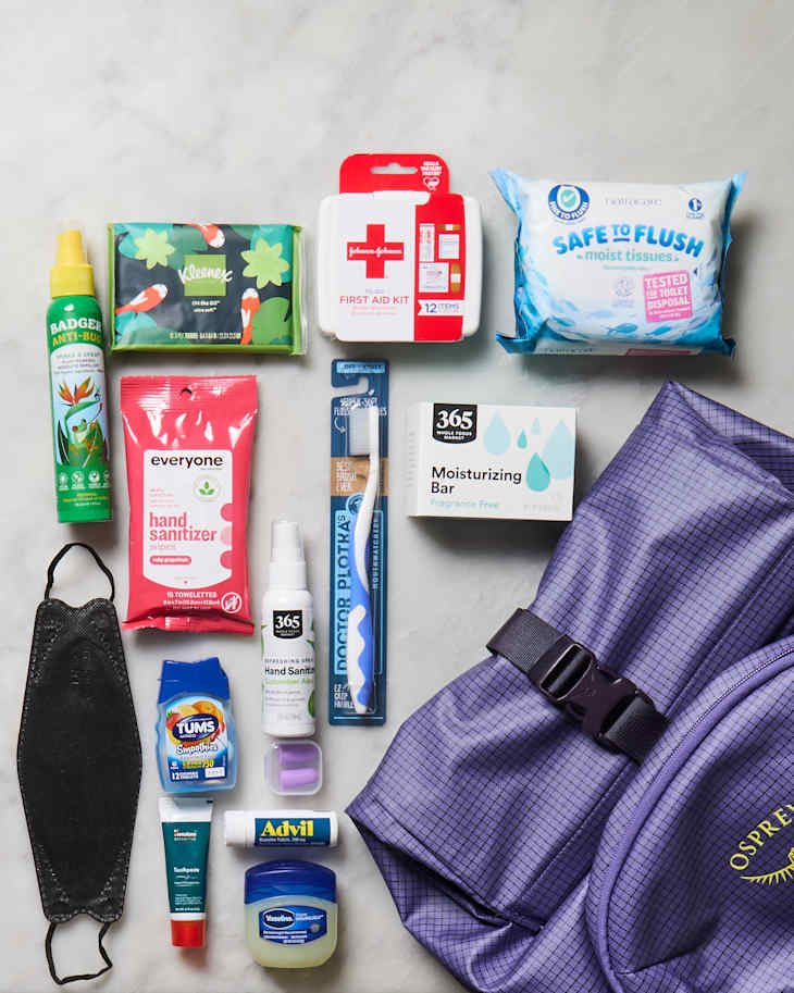 A variety of personal care items including hand sanitizer, a first aid kit, tissues, and a purple backpack.