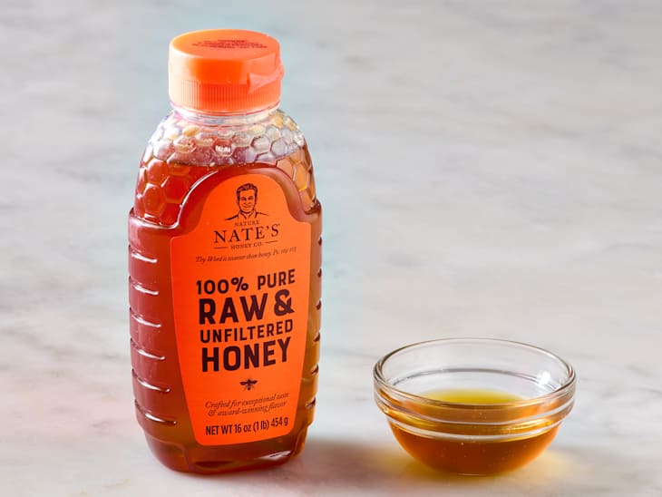 Nature Nate's honey in a bottle, with some in a small bowl to the right