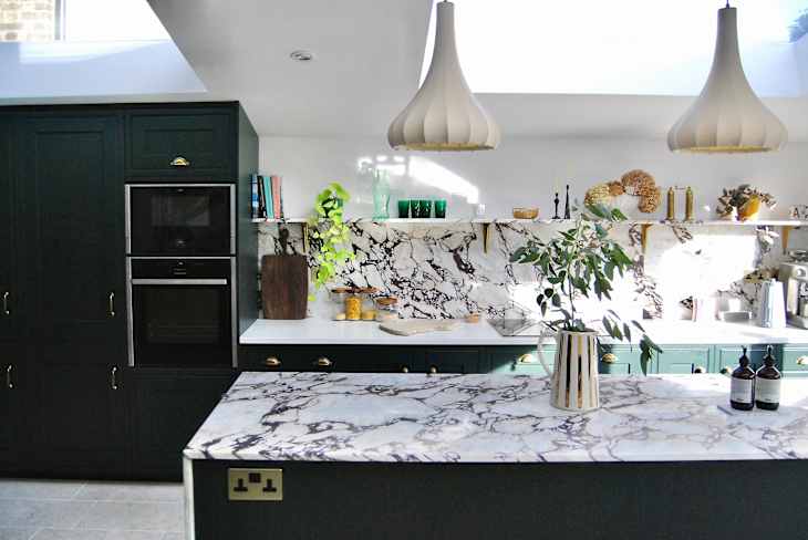 Kitchen with green cabinets, marble island, and large skylights.