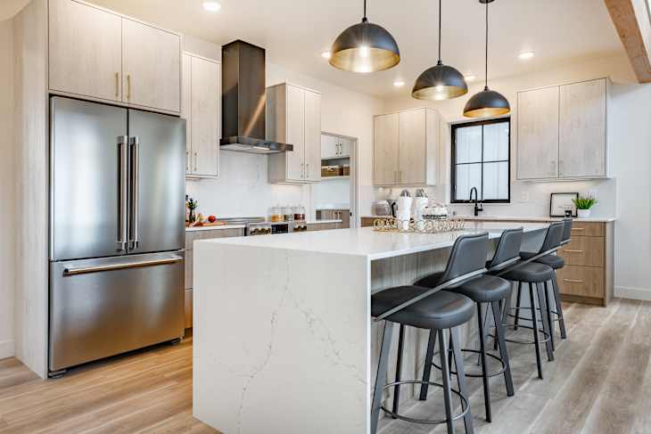 Kitchen and dining room interior with light colors aqua blue hardwood flooring grey chairs bar stools kitchen island stainless appliances and large windows