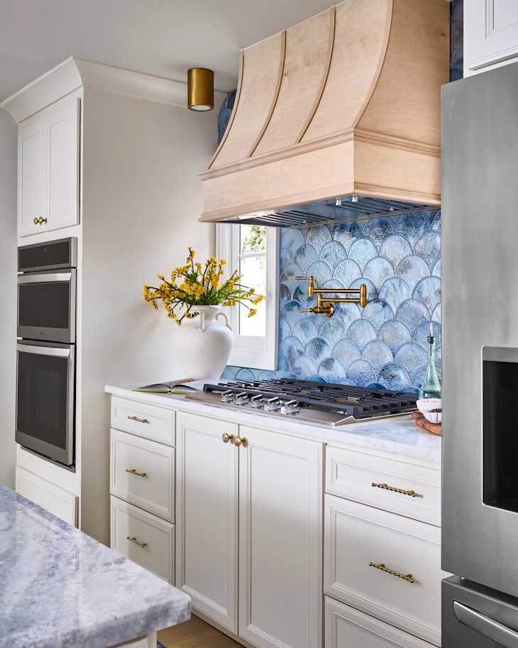 Blue scalloped tile backsplash behind stove in newly renovated kitchen.
