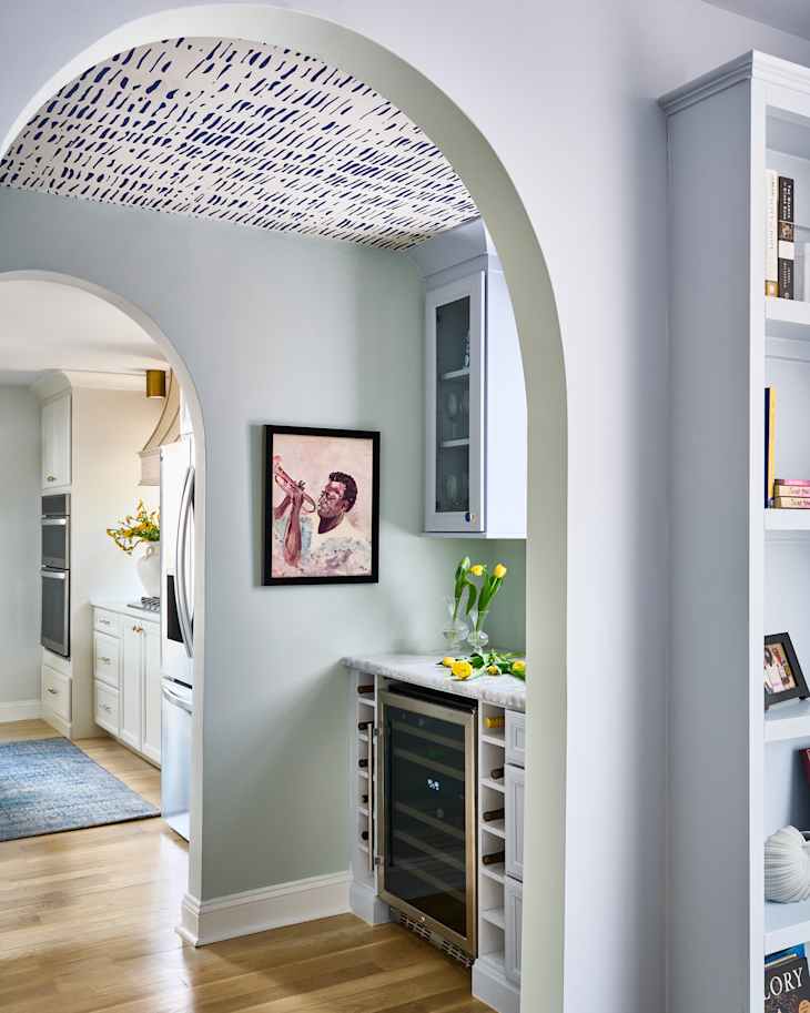 Wine fridge in annex section of kitchen with portrait artwork on the wall.