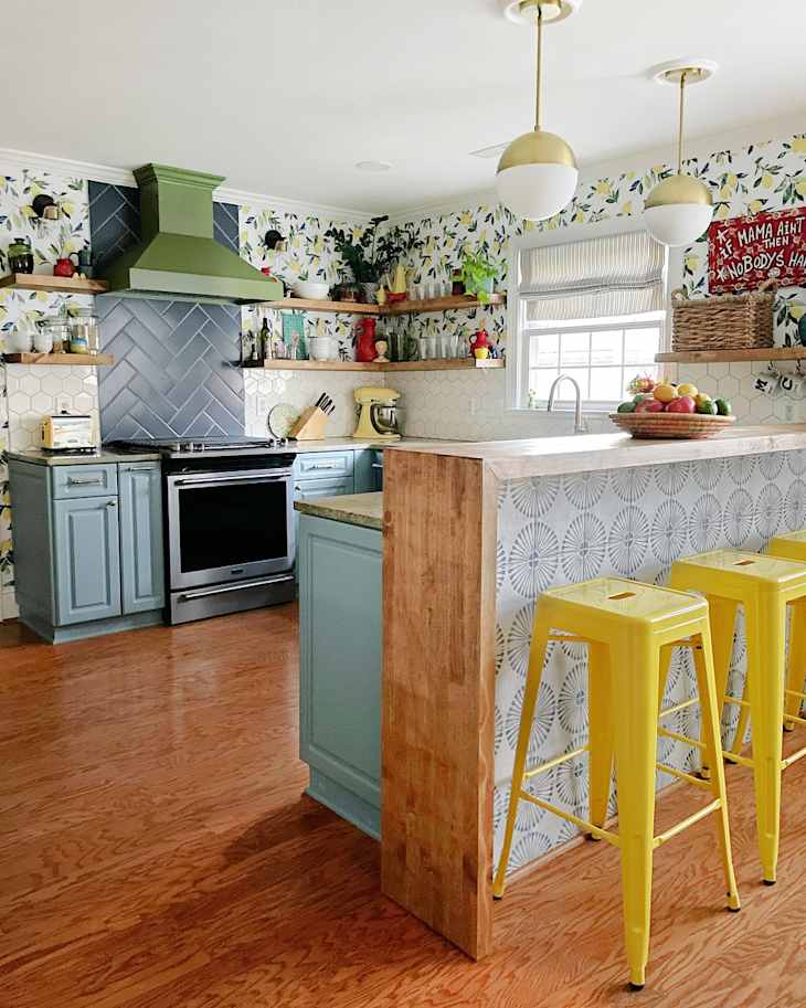 Kitchen with lemon print wallpaper, blue cabinets, and mixed media countertops