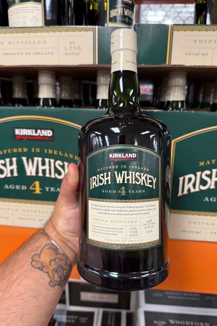 A person holding a bottle of Kirkland Irish Whiskey.