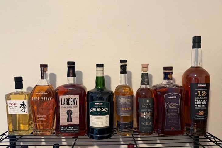 A collection of whiskey bottles on a black metal rack.