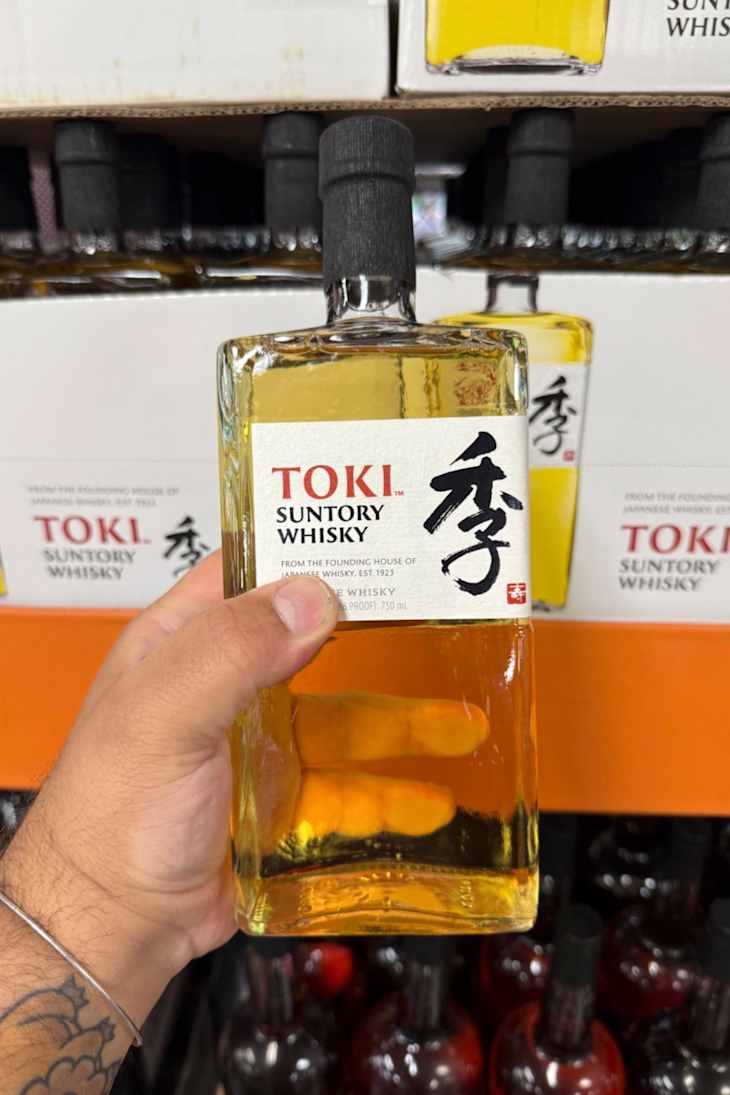 A hand holding a bottle of Toki Suntory Whisky.