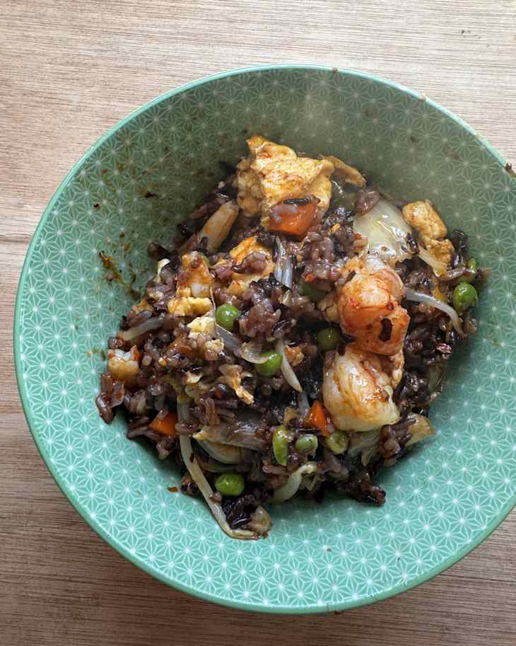 Stir-fried rice with shrimp, vegetables, and scrambled eggs in a green patterned bowl.